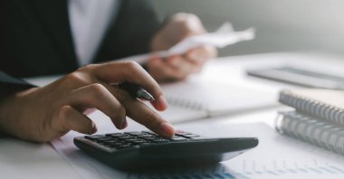  İş adamı ya da muhasebecinin el ele tutuşma kalemini kapatın. Hesap makinesi üzerinde çalışarak iş verilerini ve mali muhasebe kavramını hesaplayın.