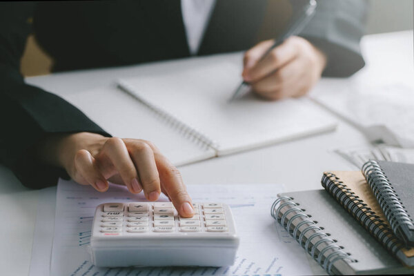 Woman hand using calculator and writing make note with calculate about finance accounting.finance accounting concept