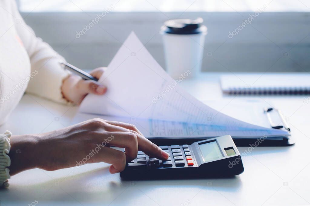 Women using calculator and calculating bills in home office.