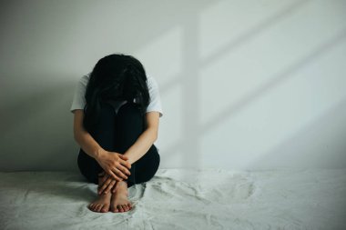 Depresyondaki kadın dizine sarılıp ağlar. Üzgün kadın boş bir odada tek başına oturuyor.. 