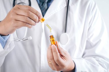 Doktor elinde bir şişe kenevir yağı, kenevir yaprağı, alternatif ilaç, CBD kenevir yağı içeren tıbbi marihuana ürünleri tutuyor.,