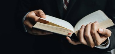 Adam kitap okuyor, yakın çekim bir el ve bir kitap gösteriyor. Eğitim kavramları