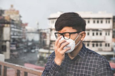 Nefes alamıyorum. Hava kirliliği ve toz parçacıklarına karşı solunum maskesi takan adam güvenlik sınırlarını aşıyor. Sağlık, çevre, ekoloji konsepti. Alerji, baş ağrısı..