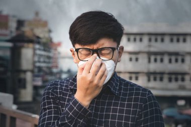 Nefes alamıyorum. Hava kirliliği ve toz parçacıklarına karşı solunum maskesi takan adam güvenlik sınırlarını aşıyor. Sağlık, çevre, ekoloji konsepti. Alerji, baş ağrısı..