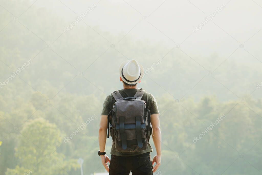 Hiker with backpack standing on street and enjoying mountain.Concept of success