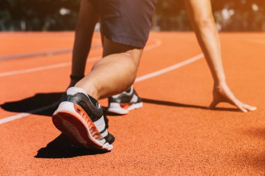 Koşucular atletik koşu pistinde. Genç adam gün batımında antrenman yapıyor. Sağlıklı yaşam tarzı ve spor anlayışı.