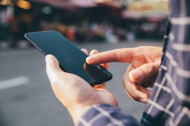 Şehirdeki alışveriş caddesinde akıllı telefon kullanan, arama yapan veya sosyal ağlar kavramını kullanan erkeklerin yakın plan görüntüsü, 