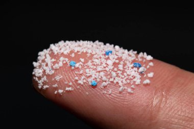 Micro plastic.Small Plastic pellets on the finger clipart