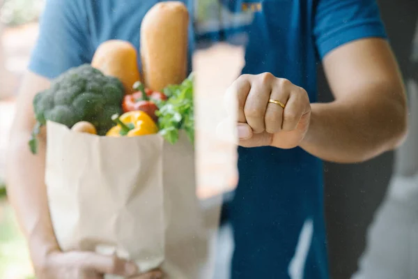 Delivery man holding paper bag with food knock on the door.Online shopping