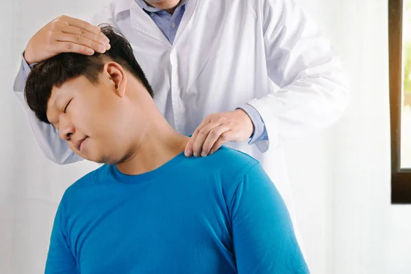 Doktor fizyoterapist, klinikte ya da hastanede erkek hastaya boyun masajı yapıyor. 
