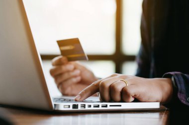 İnternetten alışveriş konsepti. Evde online alışveriş için kredi kartı tutan eller, genç sahiplerin iş başarısı..