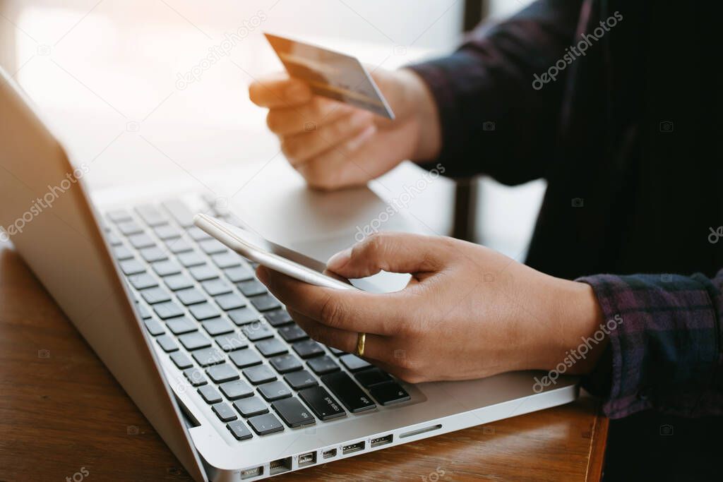 Close up  hands making online payment.Man's hands holding a credit card and using smart phone for online shopping