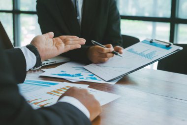 İki iş adamı birlikte çalışıyor ve toplantı odasındaki iş grafikleriyle analiz ediyorlar..