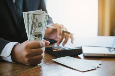 Hesap makinesi kullanan ve elinde para tutan bir işadamı Ticaret Masraflarını hesaplar. Tasarruf Finans Konsepti