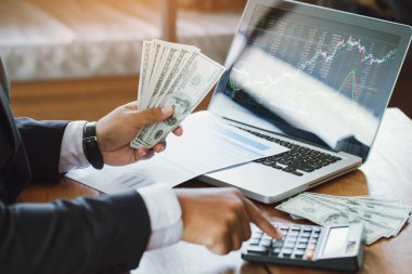 Hesap makinesi kullanan ve elinde para tutan bir işadamı Ticaret Masraflarını hesaplar. Tasarruf Finans Konsepti