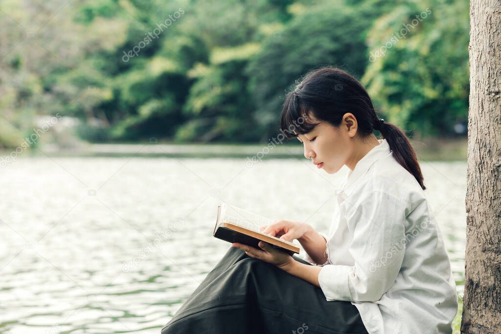 Woman reading Bible in the morning on nature background.concept for faith, spirituality and religion