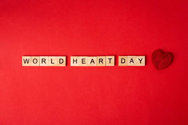 World Heart Day concept.Red heart with world heart Day text on red paper background