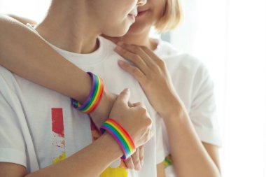 Gökkuşağı bilekliği takan lezbiyen çift birbirlerini kucaklıyor. Homofobi ve transfobiye karşı uluslararası gün için