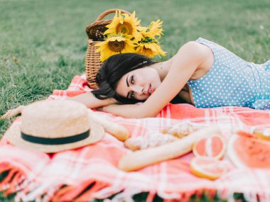 Genç bir kadın yazın piknikte yatıyor.