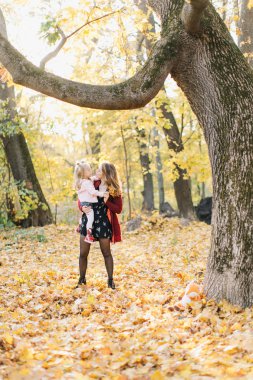 Güzel kızı ile Genç Anne altın sonbaharda parkta yürüyüş. Gül bakalım, bir selfie almak iyi eğlenceler.