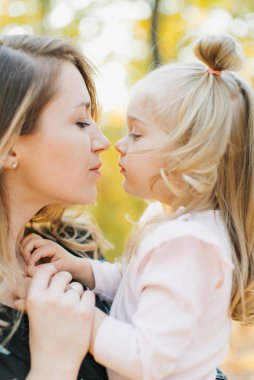 Güzel kızı ile Genç Anne altın sonbaharda parkta yürüyüş. Gül bakalım, bir selfie almak iyi eğlenceler.