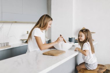 Anne ve kızı mutfakta yemek pişiriyor.