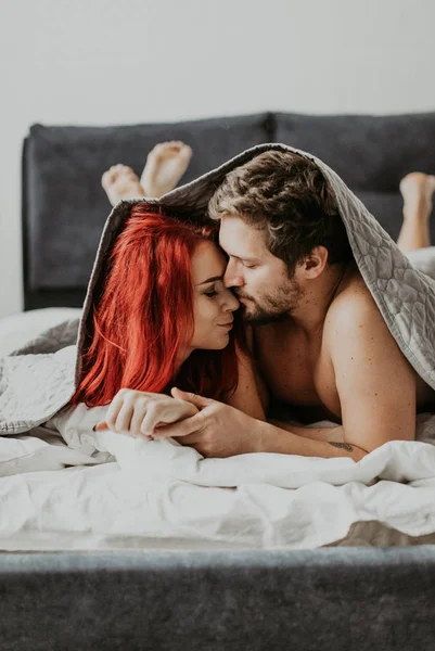 Beautiful loving couple kisses in bed