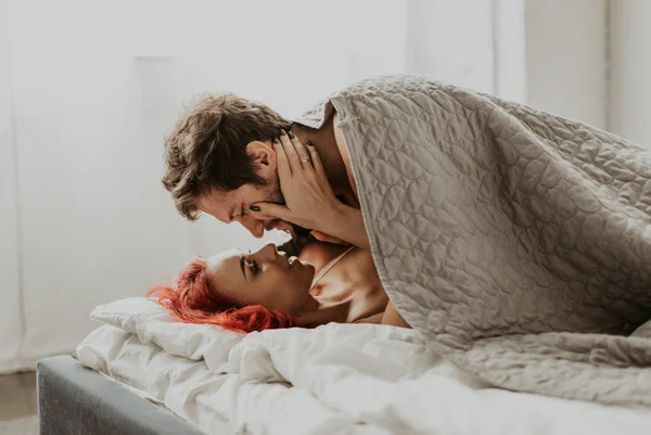 Beautiful loving couple kisses in bed