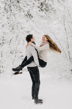 Aşık karlı ormanda, sarılma, Öpüşme ve zevk yürüme çift.