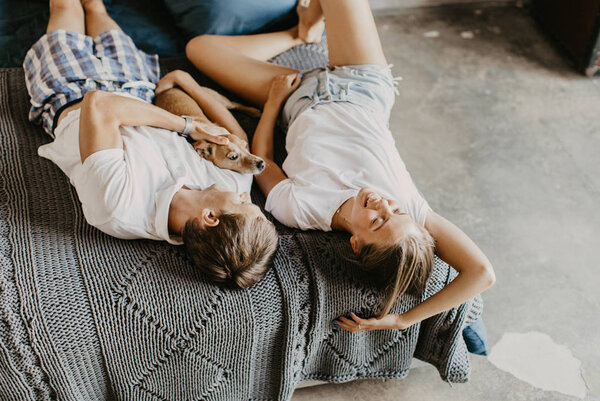 Beautiful couple in love laughs and plays with a small dog