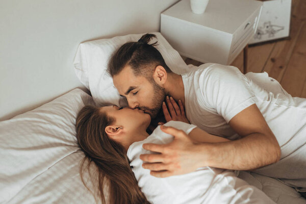 красивая любящая пара целуется в постели