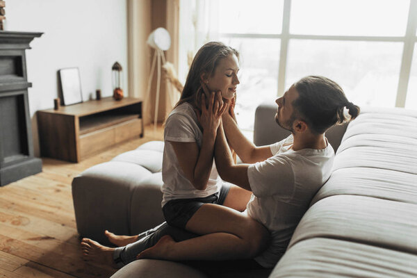 Young romantic couple is kissing and enjoying the company of each other at home