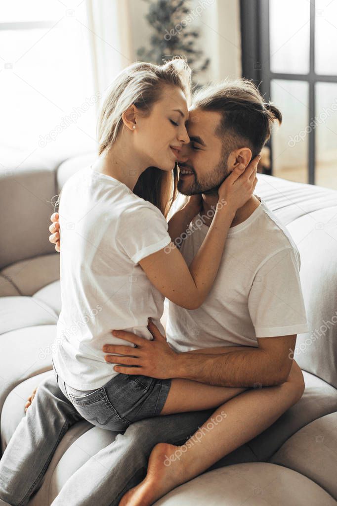 Young romantic couple is kissing and enjoying the company of each other at home