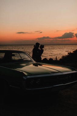 Okyanusun kenarında birbirine aşık bir çiftin silueti.