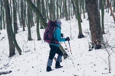 Genç kız sırt çantası ile yokuş yukarı kış orman zamları