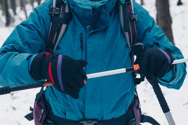 Kvinna med ryggsäck justera trekking poole i vinter skog — Stockfoto