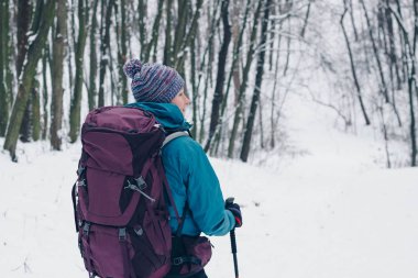Sırt çantası ile genç kız bir yana yokuş aşağı kış orman hiking görünüyor