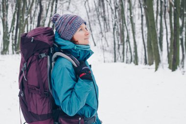 Sırt çantası ile genç kız kış ormanı hiking arar. Sağ taraftan bak