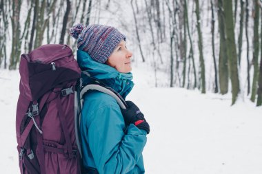 Sırt çantası ile genç kız kış orman'da yürüyüş arar. Sağ taraftan bak