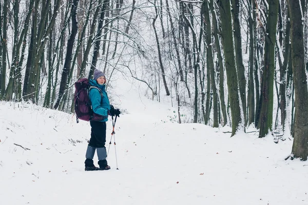 Ung flicka med ryggsäck ser undan bor på stigen i skogen vinter — Stockfoto