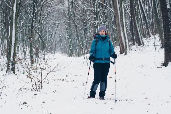 Молода дівчина з рюкзаком ходить по зимовому лісі Стокове Зображення