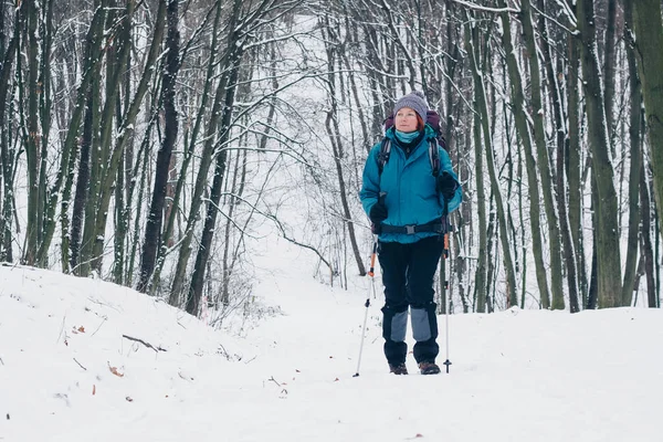 Молода дівчина з рюкзаком пішохідний підйом через зимовий ліс Стокове Фото