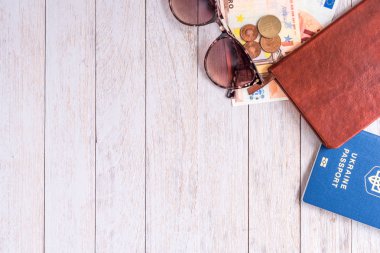 Flatlay seyahat: pasaport, cüzdan, para ve bej kurullarında köşedeki güneş gözlüğü