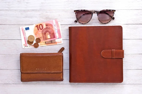 Travel flatlay: wallet, pocketbook, money and sunglasses on white boards