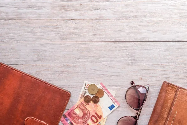 Reiseflach: Portemonnaie, Geldbörse, Geld und Sonnenbrille auf der Rückseite beiger Bretter — Stockfoto