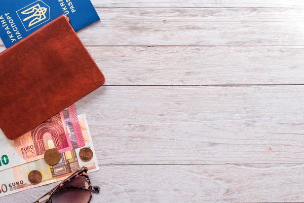 Travel flatlay: passport, pocketbook, money and sunglasses on white boards