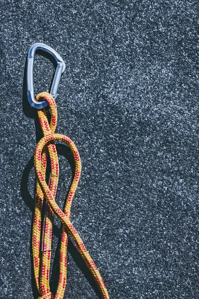 Mousqueton avec corde orange vif sur une surface texturée en feutre de toiture avec de nombreuses petites pierres grises — Photo