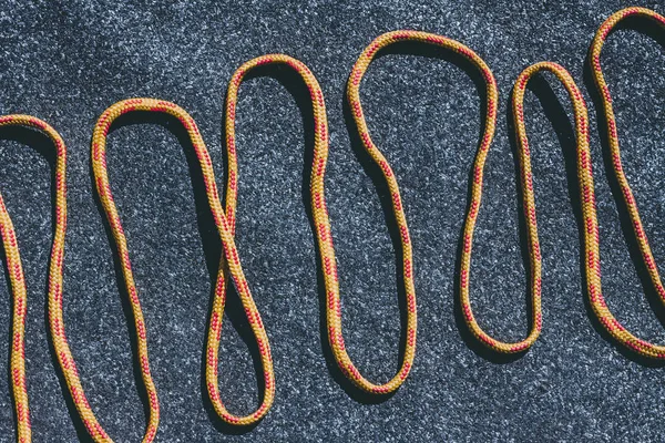 Leuchtend orangefarbenes Seil auf einer strukturierten Dachfilzoberfläche mit vielen kleinen grauen Steinen — Stockfoto