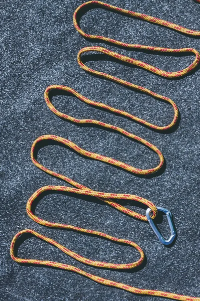 Helder oranje touw met een kleine karabijnhaak op een texured dakoppervlak met veel kleine grijze stenen — Stockfoto