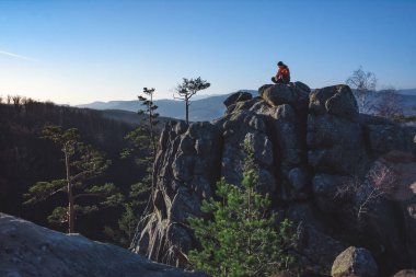 Genç adam gün doğumunda kayanın tepesinde oturmuş meditasyon yapıyor.